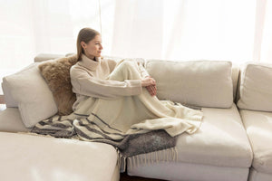 Arrangement aus Decke und Kissen aus Royal Alpaka auf hellem Sofa