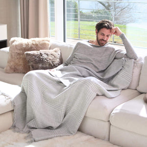 Mann kuschelt auf dem Sofa mit Alpaka Wolldecke MATEA