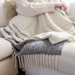 Frau kuschelt auf Sofa mit Alpaka Boucle Wolldecke MULLIDA