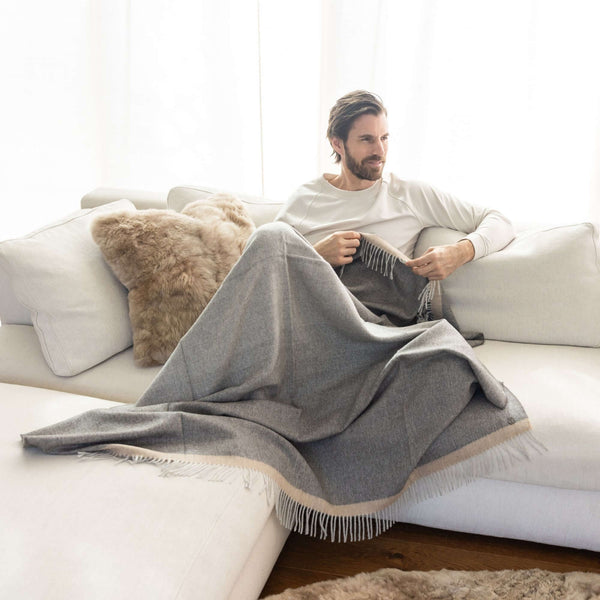 Mann auf Sofa mit Plaid MERIMA aus Alpakawolle mit Verlauf