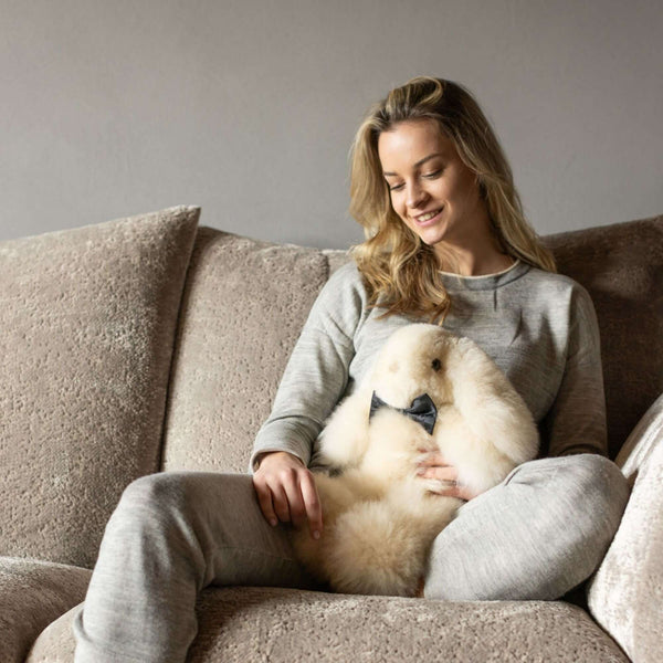 Frau kuschelt auf dem Sofa mit Stofftierhase MILO aus Alpaka