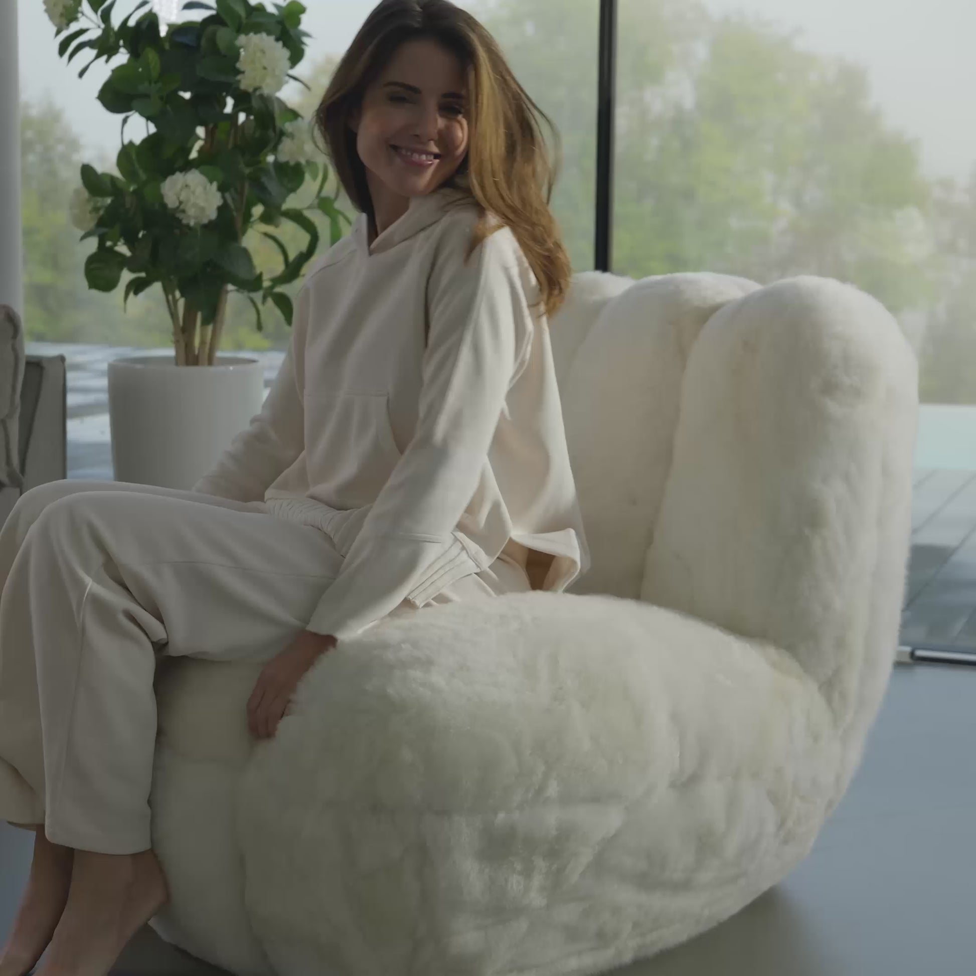 Frau sitzt auf Toe Chair Sessel DEDO im Wohnzimmer 